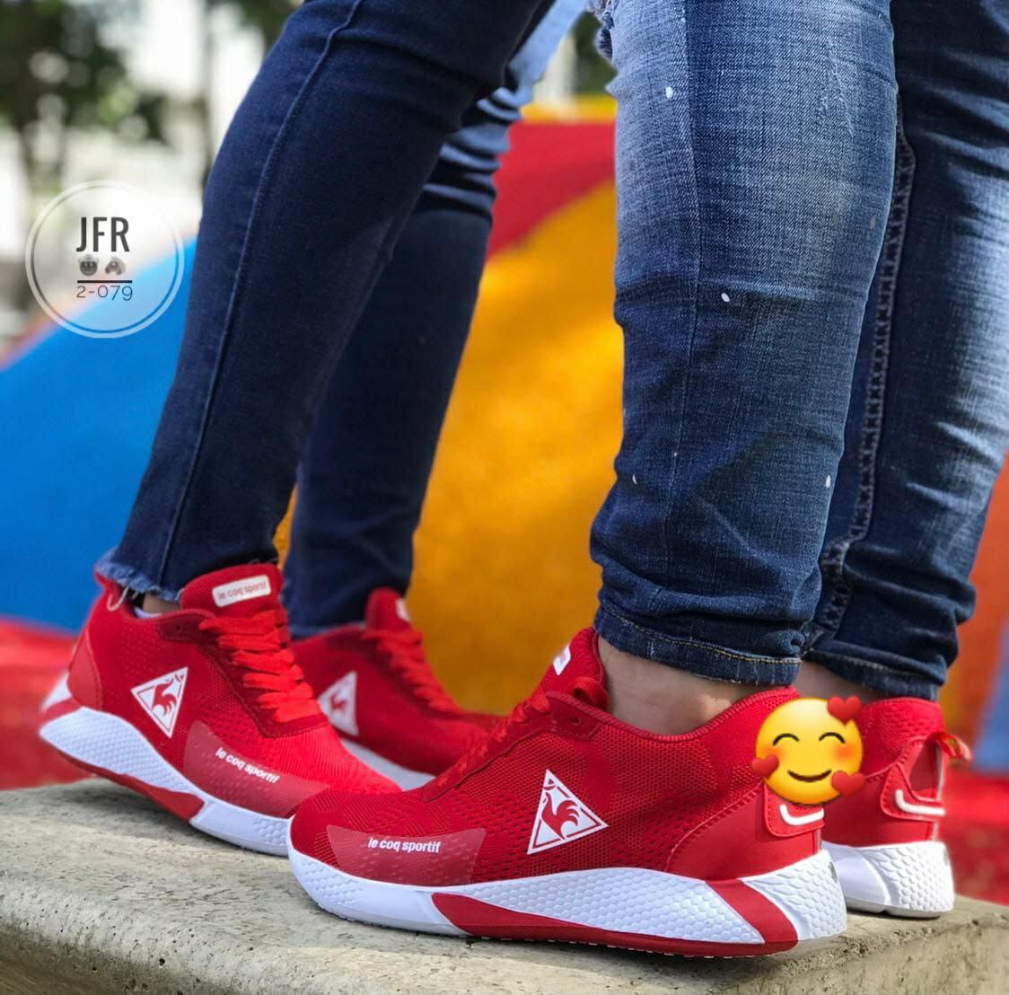 Pies con zapatillas rojas y blancas, jeans azules, fondo de parque con colchoneta multicolor.